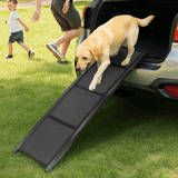 A golden retriever walks down a black foldable ramp exiting an SUV trunk onto a grassy lawn.