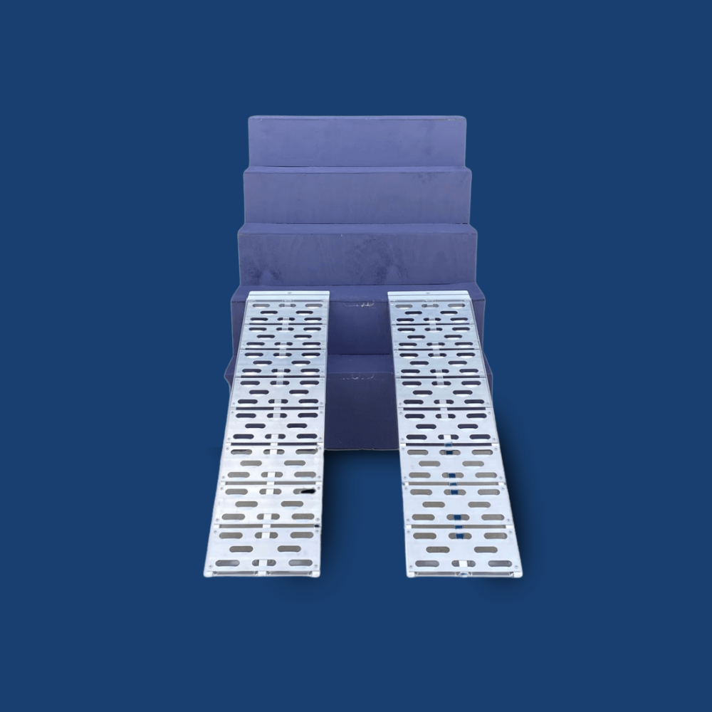 Wheelchair positioned on aluminium ramps, angled on blue steps.