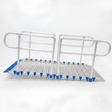 A metal rolling ramp with integrated handrails and a slotted deck plate, featuring blue protective end caps and blue grip pads, shown on a white background.