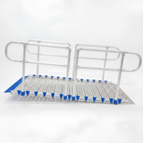 A metal rolling ramp with integrated handrails and a slotted deck plate, featuring blue protective end caps and blue grip pads, shown on a white background.