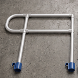 A silver metal U-shaped tubular guardrail or safety barrier with blue plastic end caps, photographed on a textured gray concrete floor.