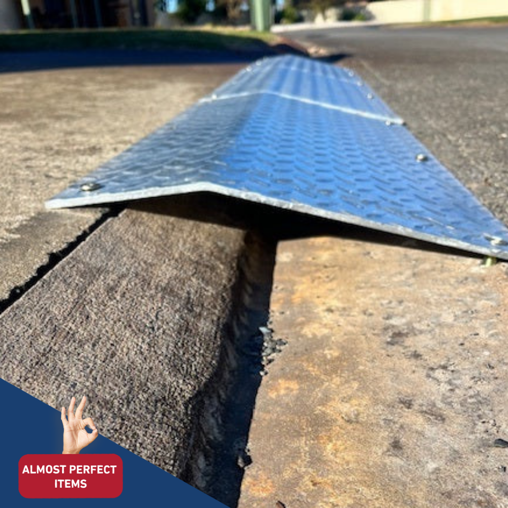 Side angle view of a portable aluminium kerb ramp installed over a street gutter, part of the “Almost Perfect Items” range