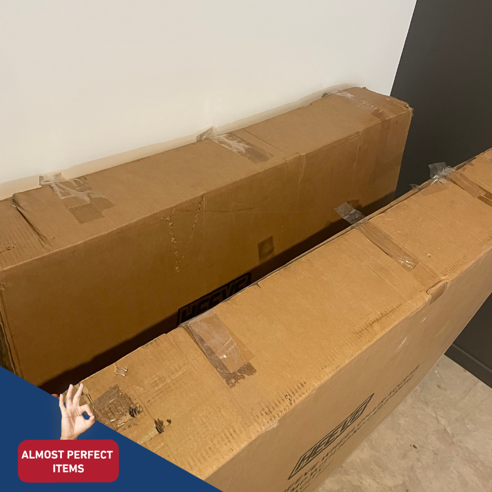 Two large cardboard boxes stacked against a white wall with 'Almost Perfect Items' logo.