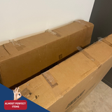 Two large cardboard boxes stacked against a white wall with 'Almost Perfect Items' logo.