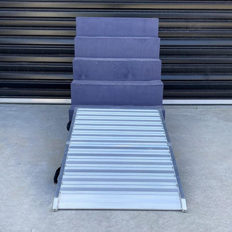 Aluminium ramp leaning against a roller door on dark surface.