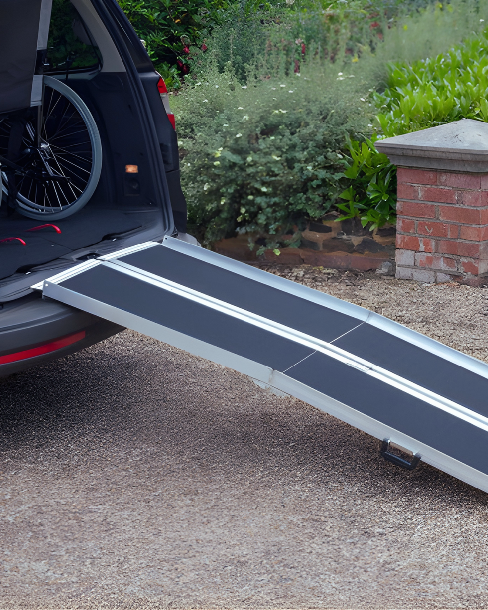 Ramp extended from a vehicle with a garden and brick wall in the background