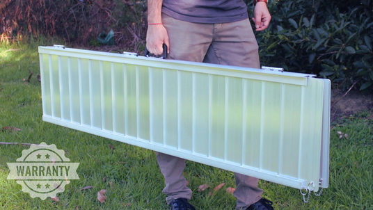 Person holding an aluminium ramp outdoors with a 'Warranty' label in the corner.