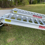 Whipps 6.5 tonne ramps side view against a trailer with green grass in background