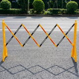 Yellow and black road barrier on a road with green bushes in the background
