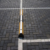 Base Guard® 2000mm Rubber Wheel Stop on a brick pavement