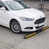 White car parked next to aBase Guard® 2000mm Rubber Wheel Stop on a road.