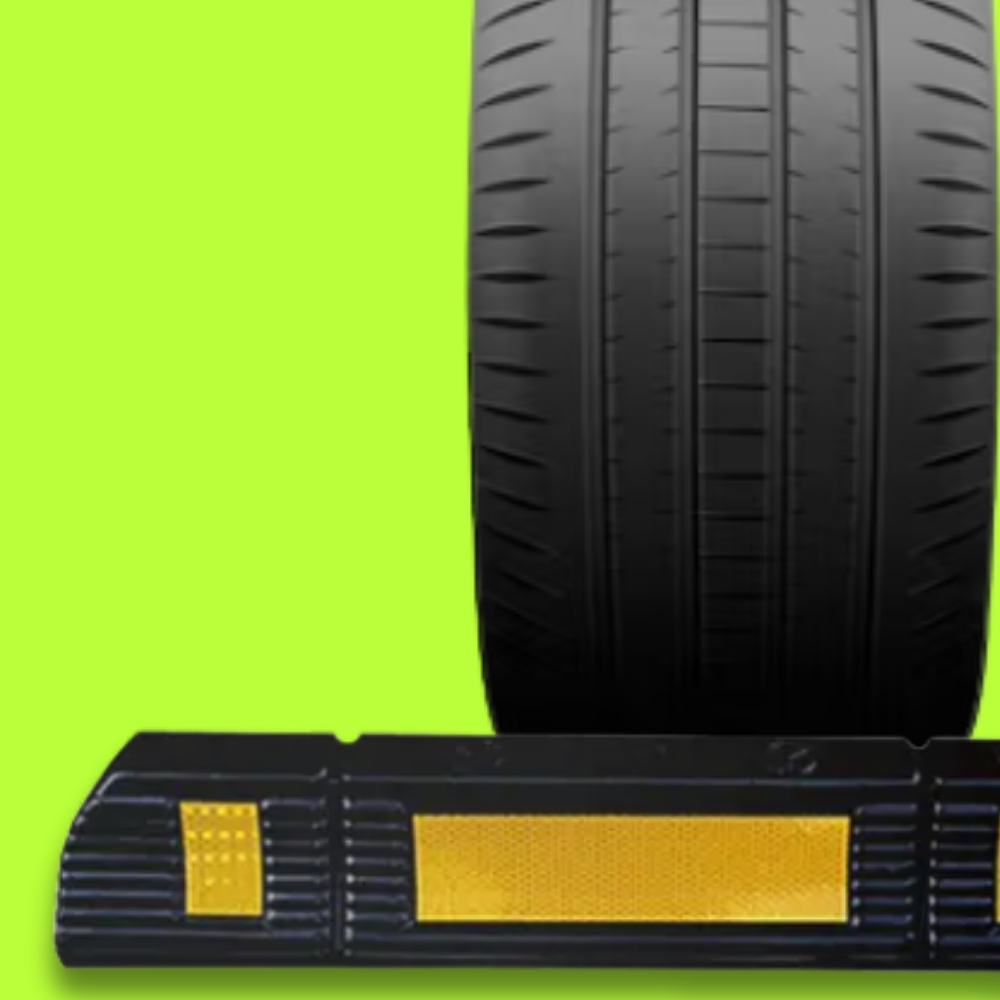 Car tire on a black and yellow traffic cone against a green background