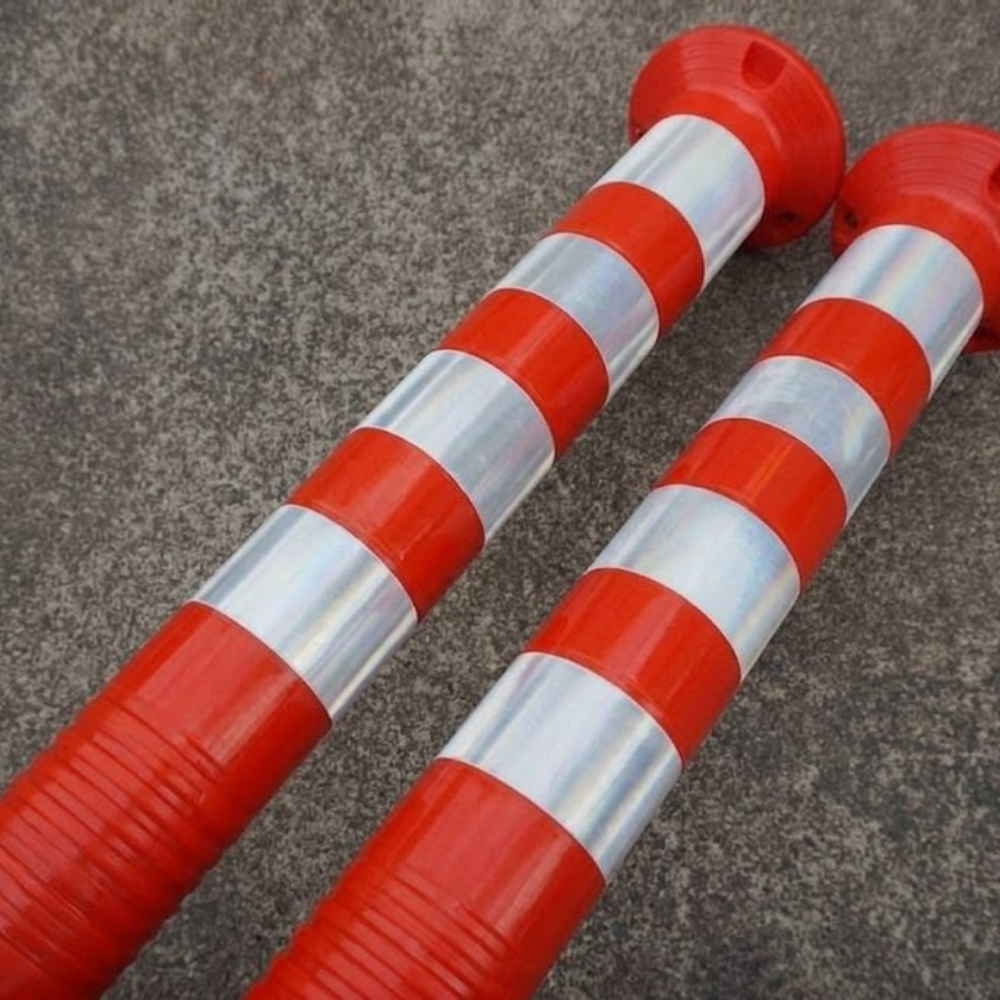 Two red and silver striped barriers on a concrete surface