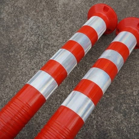 Two red and silver striped barriers on a concrete surface