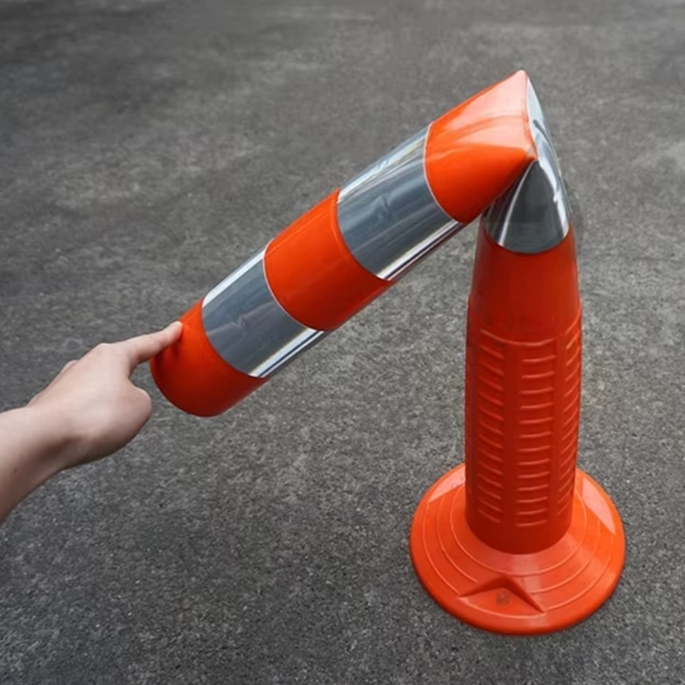 Orange traffic cone with reflective silver stripes on a gray pavement.