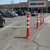 Red and white striped poles in a parking lot with a Mega-Mart store in the background.