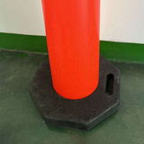 Orange traffic cone with black base on a green floor.