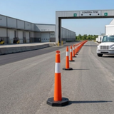 Row of orange traffic cones on a road with a loading zone sign in the background.