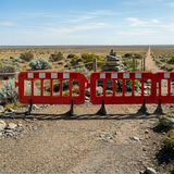 Red barrier in a desert landscape with cairn and pathway