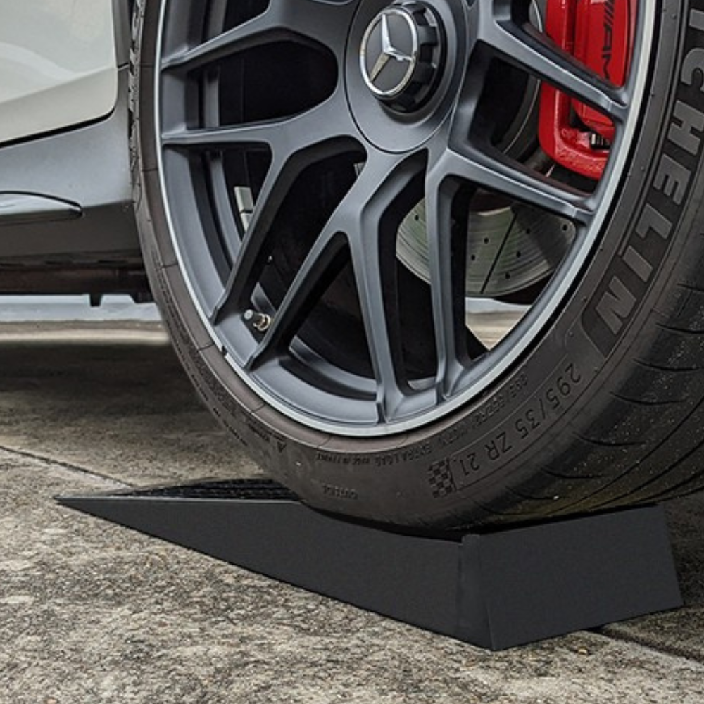 Close-up of a car wheel with a tire on a black ramp, featuring a Mercedes-Benz logo.