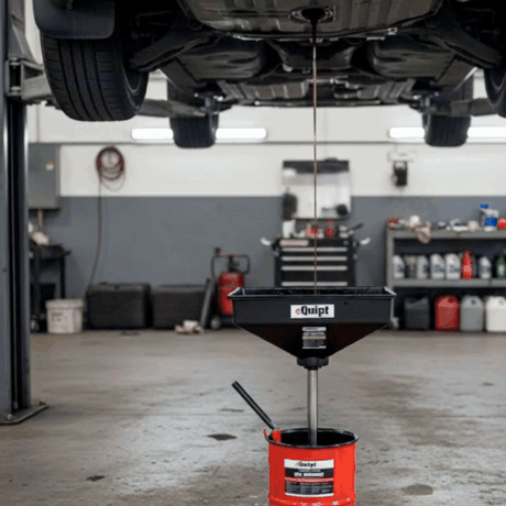 Car being serviced with an oil drain pan and funnel in a garage setting