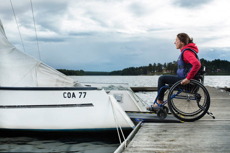 FEAL iRamp folding aluminium wheelchair ramp in use, wheelchair rolling from a jetty onto a boat