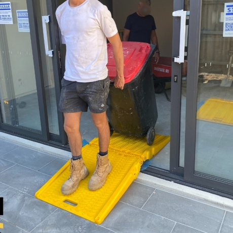 Person pushing a trolley over the ramp through a doorway.