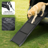 Dog using a black pet ramp with vehicle and grass background
