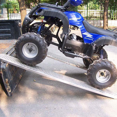 Blue and black ATV on a metal ramp with trees in the background