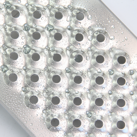 A close-up macro shot of a perforated aluminum surface (likely a ramp) covered in water droplets, highlighting its texture.