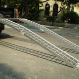 Heeve® 250kg 2.23m x 300mm Curved Non-Folding Aluminium Loading Ramp on a street with a building and trees in the background