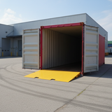 Open shipping container with a yellow mat on a concrete surface, with a building in the background.