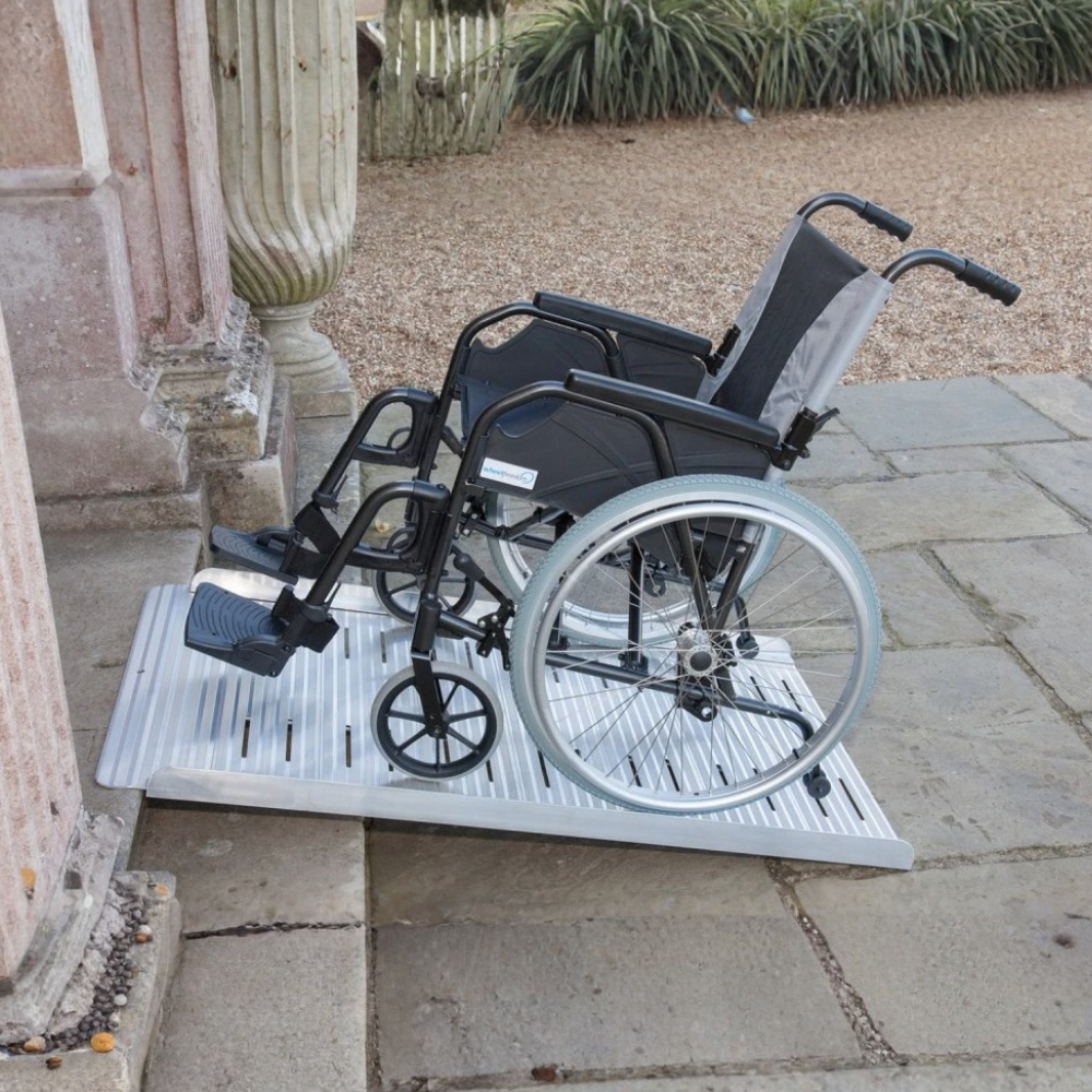 Wheelchair on Heeve® Aluminium Non-Folding Wheelchair Ramp with Open Grid Deck in an outdoor setting