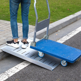 Person using a blue and silver hand truck with a ramp to navigate stairs.