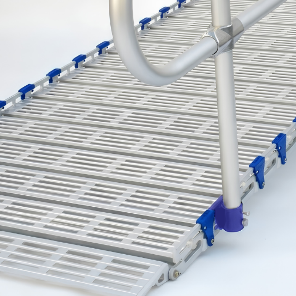 A close-up of a white plastic slatted ramp or walkway panel with blue connector clips and a silver metal support post.