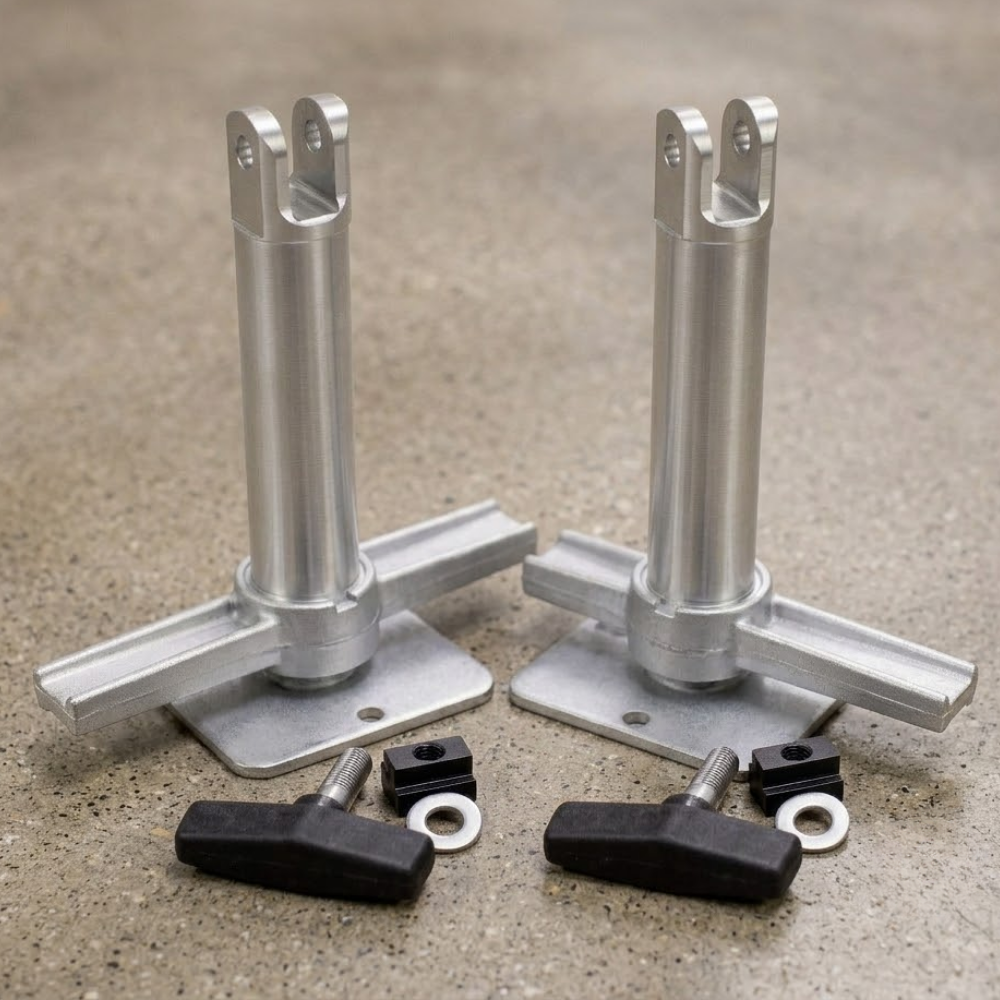 Two silver aluminum leveling feet with flat mounting plates and vertical posts, shown with four black adjustment knobs and small silver washers on a textured gray surface.