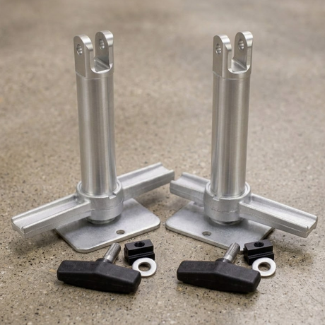 Two silver aluminum leveling feet with flat mounting plates and vertical posts, shown with four black adjustment knobs and small silver washers on a textured gray surface.