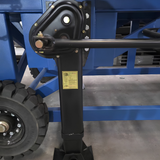 Close-up of a black heavy-duty mechanical linkage arm and vertical support bracket attached to a blue metal frame, with a black tire visible on the left and a gray concrete floor below.