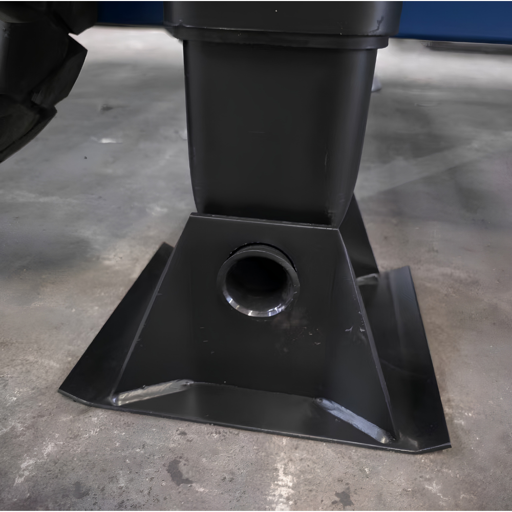 A close-up of a black metal mounting bracket or base with a circular opening, photographed on a concrete floor.