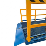 A blue and yellow industrial yard ramp approach plate with a metal grid floor and safety railings, shown against a plain white background.