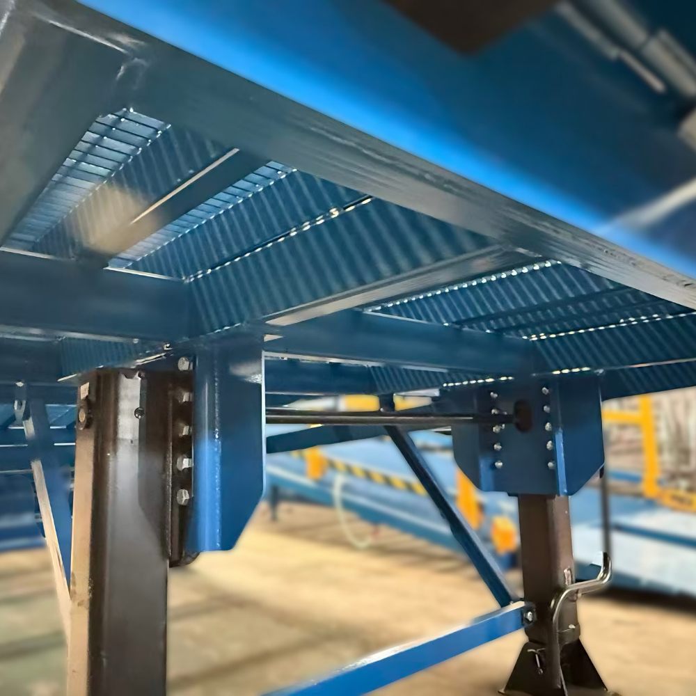 Close-up of a blue metal industrial structure with slatted panels and support beams in a workshop or factory setting.