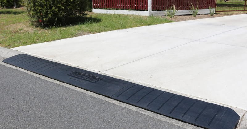 Black rubber mat on a concrete surface with grass and a building in the background