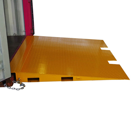 Side view of a yellow Heeve self-supporting forklift container ramp placed in front of an open shipping container, showing the forklift tyne slots and the anti-skid surface.