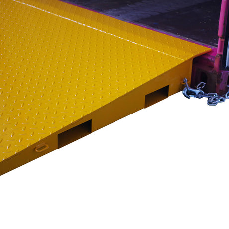 Close up view of a yellow Heeve self-supporting forklift container ramp placed in front of an open shipping container, showing the forklift tyne slots and the anti-skid surface.