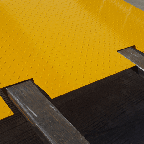 Close up view of Heeve self-supporting forklift container ramp placed in front of an open shipping container, showing the forklift tyne slots and the anti-skid surface.