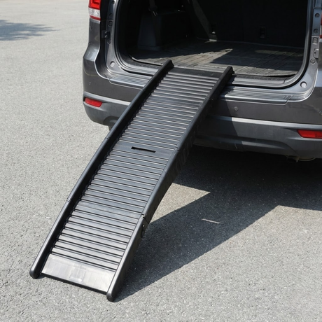 Black pet ramp extended from an open car trunk on a paved surface