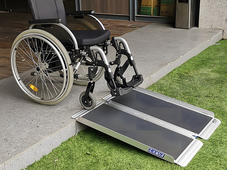 Wheelchair beside a folding aluminium ramp over a step at a doorway