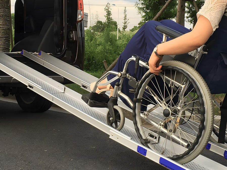 Wheelchair rolling up a pair of telescopic channel ramps into a car