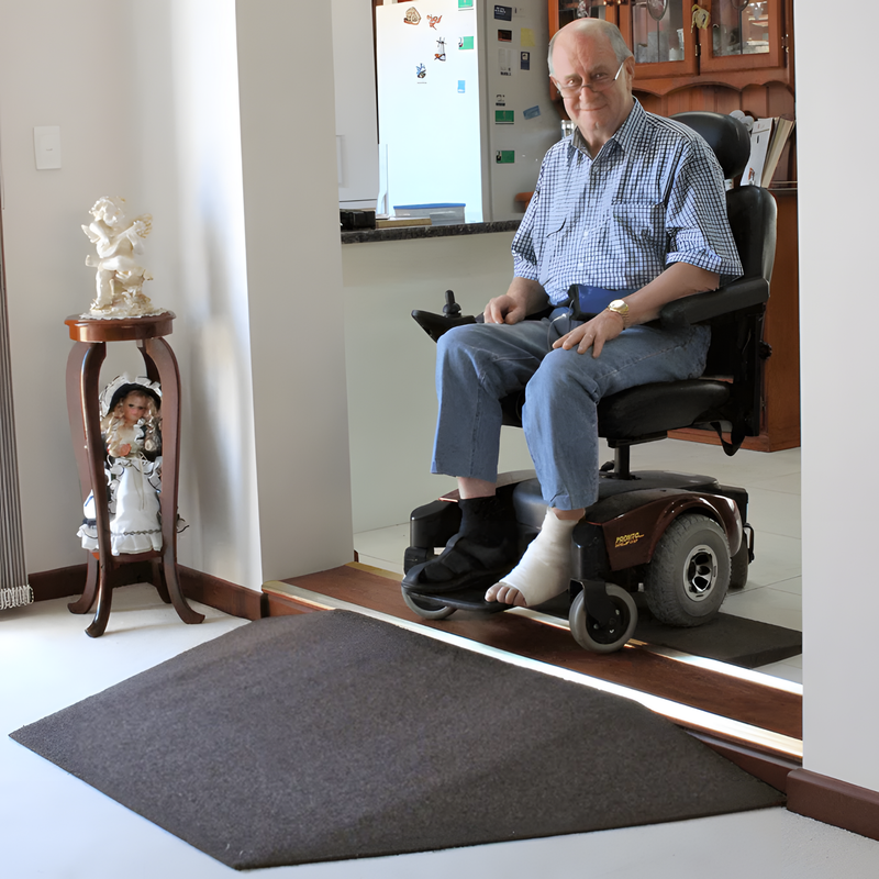 Man using a wheelchair on a home ramp with a small round table and figurines in the background.