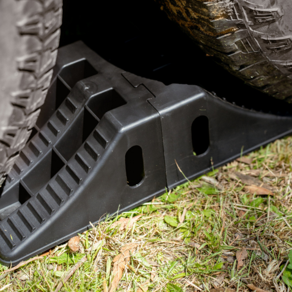 Black tire jack on grass with a vehicle tire in the background